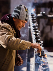 Pilgrim lighting an oil lamp at the Muktinath temple in the Mustang region of Nepal