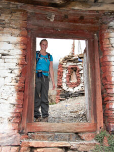 Trekker standing in the ancient doorway to Phu on the Nar Phu trek