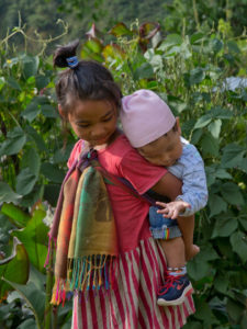 Young girl taking care of her little brother in Hellok on the Kanchenjunga trek in Nepal