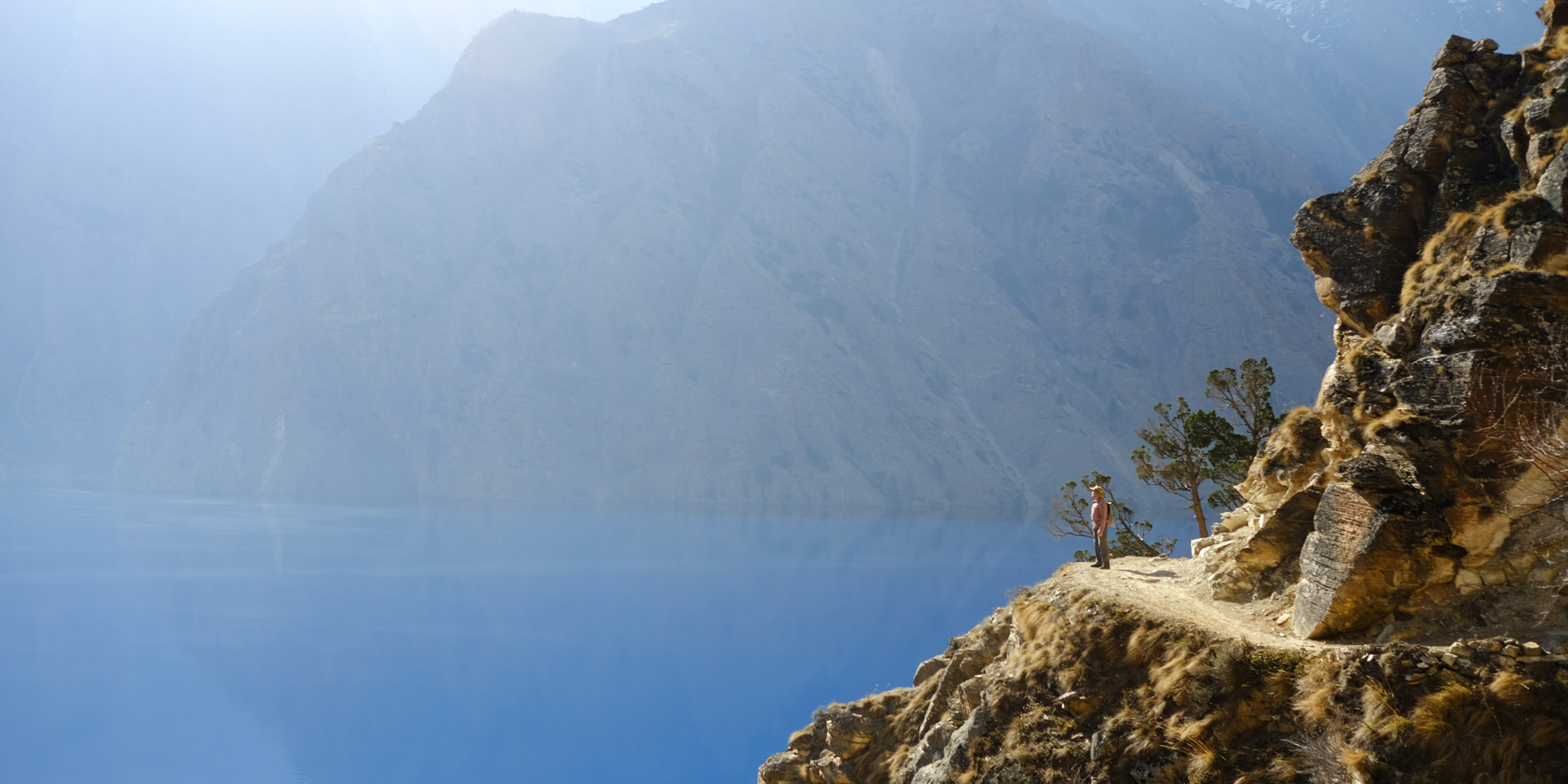 A small trekker in the grand landscape at the Phoksundo lake in Dolpo