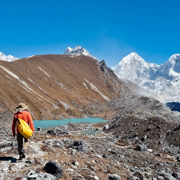 Trekker approaching Omi Tsho (Dudh Kunda) with Omi Tsho Go 6332m, Dinguing Ri, Khang Kharpo 6646m and Tragnak Ri 6801m in the background. On the Rolwaling trek in Nepal